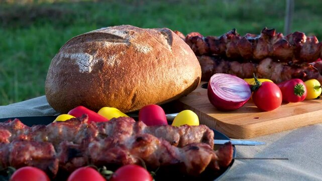 shish kebab shashlik outdoors put on a plate with salad vegetables and homemade cut bread broken linen tablecloth rest on a picnic