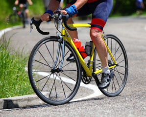 Cyclists legs pedaling powerfully on the yellow racing bike during the race on the road