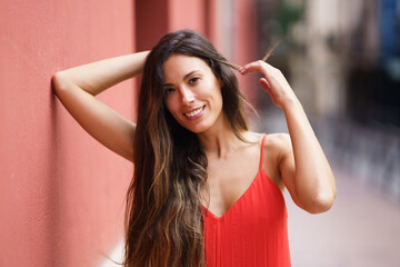 A Smiling Young Woman with Beautiful Long Hair Posing Gracefully Against a Colorful Wall