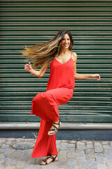 A Stylish Woman Gracefully Dancing in a Flowing Red Dress Set Against a Lush Green Background