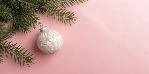 A single white Christmas ornament with gold accents rests on a pink background, partially obscured by a green fir branch.