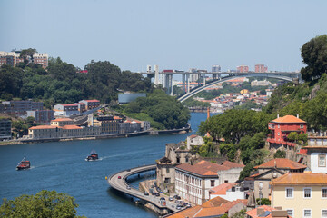 A view over the river Douro at the harbour of Porto in Portugal. The 70 m high bridge of Ponte da Arrábida, which is close to the mouth of the River and the Atlantic Ocean, is visible in the distance.