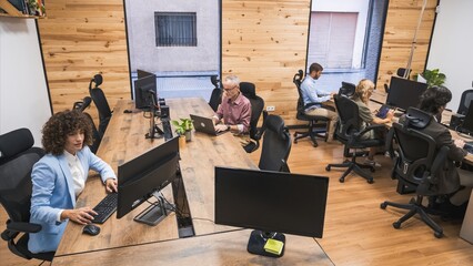 From above of business team working on computers in creative office