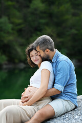 Obraz premium Happy couple sitting in front of beautiful calm lake