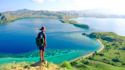 A man with a backpack on the background of the sea at Gili Lawa, Komodo National Park, Indonesia. summer background and summer holiday concept.  © Balnyes Visuals