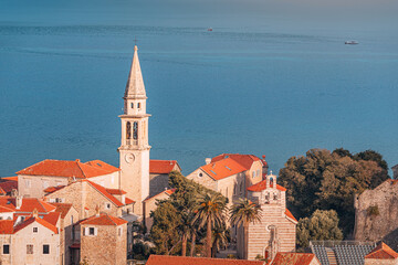Fototapeta premium Budva historic charm shines along the Adriatic coast, where red-roofed stone buildings, church towers, and medieval walls meet the turquoise sea in Montenegro