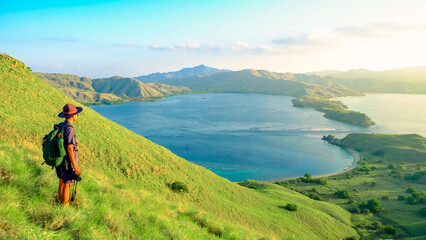 Young Asian man traveller holding camera and standing on top of Gili Lawa, Komodo National Park, Indonesia. summer background and summer holiday concept. © Balnyes Visuals