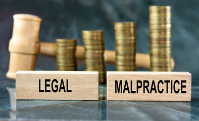 LEGAL MALPRACTICE - word on a wooden block on a background of stacks of coins