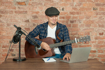 Musician recording acoustic performance singing and playing guitar with microphone
