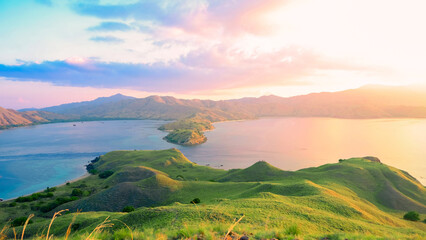 Sunset over horizon on ocean with green hill at Gili Lawa, Komodo National Park, Indonesia. summer background © Balnyes Visuals