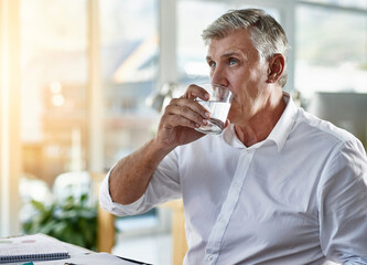 Drinking water, office and business man at desk with executive and hydration for health. Drink, glass and mature professional at financial management company with accounting paperwork and planning