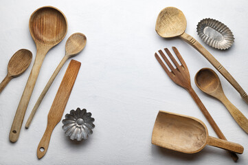 Ladles and other wooden kitchen tools on white plaster background, top view, space for text.