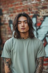 Naklejka premium Stylish urban portrait of a young man with tattoos against a graffiti wall