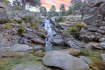 Waterfall at the Cascades des Anglais in Corsica surrounded by rocky terrain and lush forest scenery © Aquarius