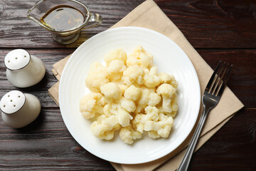 Tasty cooked cauliflower served on wooden table, flat lay