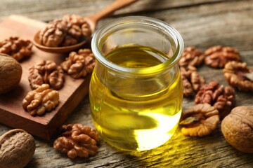 Walnut oil in jar and ingredients on wooden table, closeup