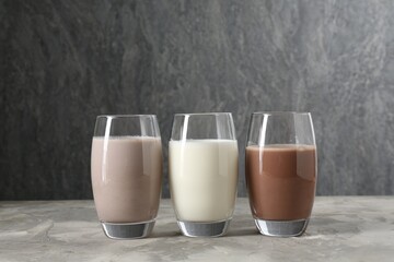 Delicious protein shakes in glasses on gray textured table