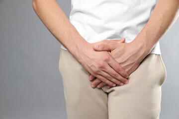STD (sexually transmitted diseases). Man suffering from symptoms on grey background, closeup