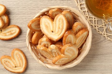 Delicious palmier cookies with tea on wooden table, flat lay