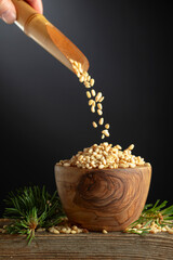 Pine nuts is poured in a wooden bowl.