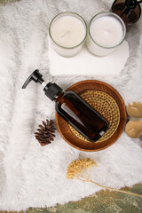 Amber Glass Pump Bottle with Wooden Plate and Spa Candles on Fluffy Decor