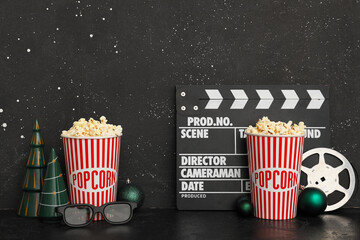 Composition with film reel, movie clapper buckets of popcorn and Christmas decorations on table...