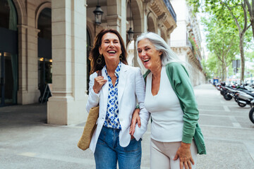 Beautiful senior women bonding outdoors in the city - Attractive cheerful mature female friends having fun, shopping and bonding, concepts about elderly lifestyle