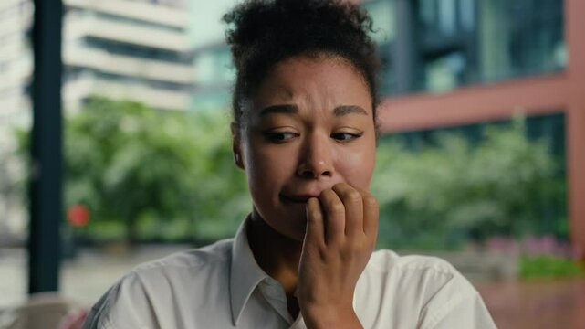 Close up face confused puzzled African American woman girl businesswoman business city bite lip worried thinking uncertainty contemplation choosing doubt hesitate female decision town outdoor employer