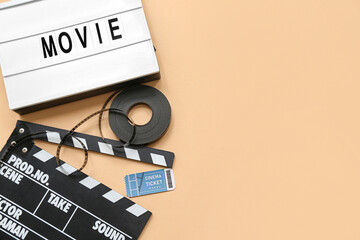 Movie clapper with word MOVIE, cinema ticket and film reel on beige background