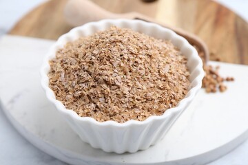 Buckwheat bran in bowl on white table, closeup