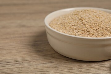 Oat bran in bowl on wooden table, closeup. Space for text