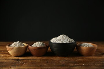 Fresh rye bran in bowls on wooden table against black background. Space for text