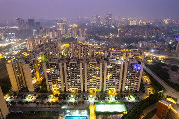 aerial drone shot looking down over skyscrapers multi storey with park in between with lights for...