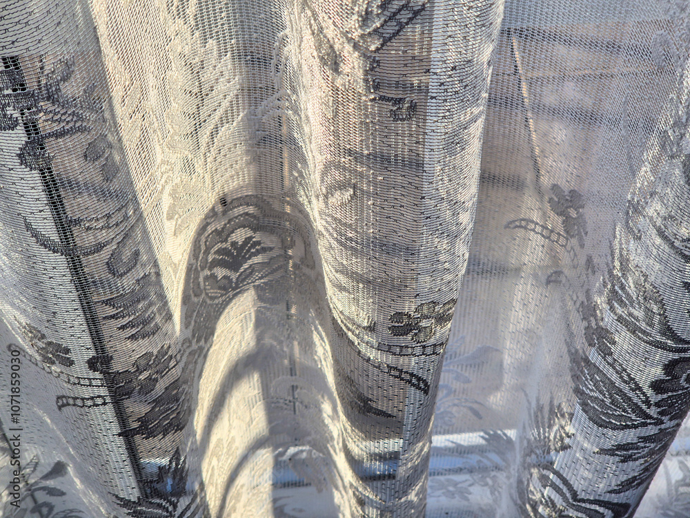 Poster close-up of delicate lace curtains softly illuminated by sunlight, creating a beautiful textured pat