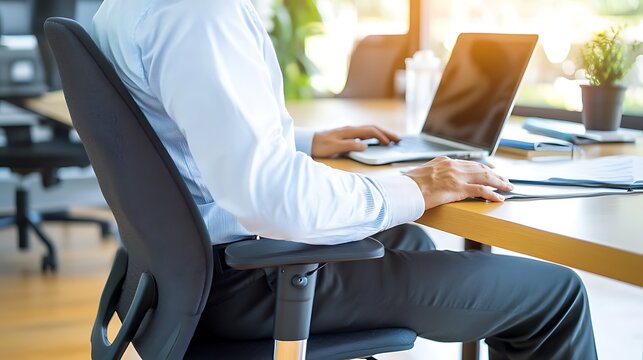 Person sitting at desk with poor posture, emphasizing the importance of ergonomic practices for maintaining health and productivity in the workplace.