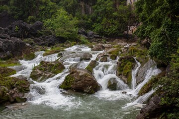 Obraz premium A babbling brook flows through a lush green mountain valley.