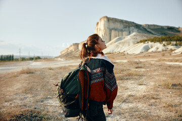 adventurous woman gazing at serene mountain horizon with backpack in tow