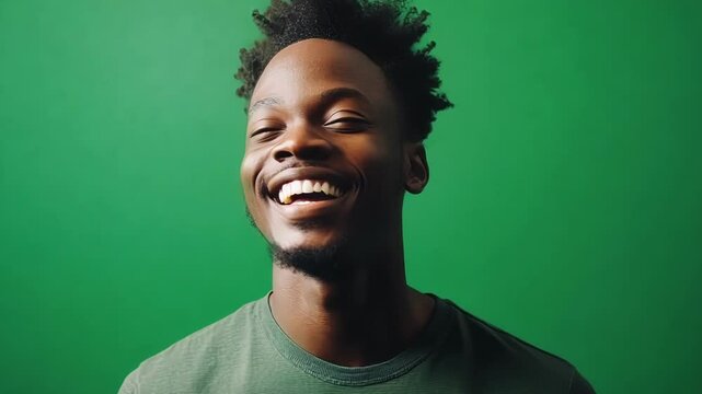 Young man is expressing joy and positivity while standing on a green screen background, perfect for replacing with any image or video