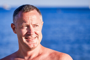 Head portrait, man on the beach looking towards the sunshine