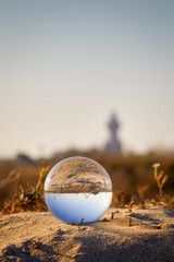 Glass ball in the evening light on the sand