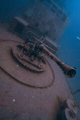 rusty metal structure of a shotgun, underwater shipwreck. Travel photography from scuba diving, adventure deep wreck exploration. Sunken boat in the deep blue ocean