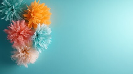 Obraz premium An array of vibrant, fluffy pom-poms in pink, orange, and blue arranged on a bright turquoise background, creating a lively and cheerful visual effect.