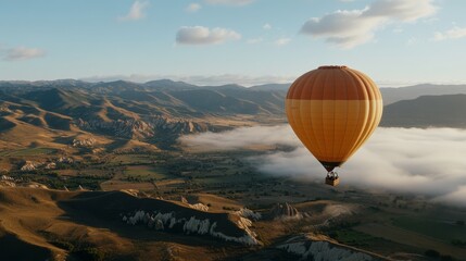 Fototapeta premium A vibrant hot air balloon floating above lush valleys and rugged mountains under a clear, expansive sky, showcasing adventure and tranquility.