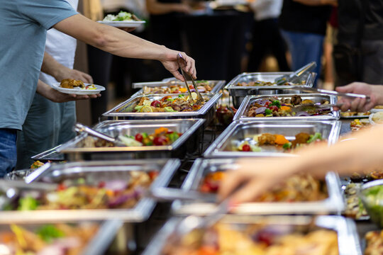 Buffet spread featuring a variety of dishes, with guests serving themselves at a catering event in an indoor setting