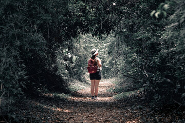 Mujer viajera adentrándose a un sendero en la jungla oscura. Fotografía estilo Dark Moody