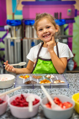 Little girl learning how to cook in a cooking class. Handmade dessert. Making chocolate candy, Child filling heart shaped mold with chocolate