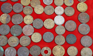 A collection of vintage Nepali coins displayed on a vibrant red background, showcasing a variety of designs and historical details.