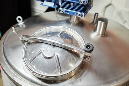Background shot of stainless tank with closed lid for cider pasteurization or brewing beer in factory workshop, copy space