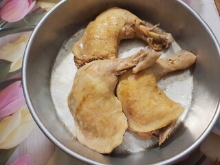 Close up of home cook grilled chicken thigh in a metal tray on a wooden table