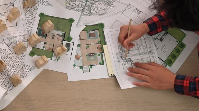 Architect and safety engineer discussion about building construction use blueprint on table with architectural document, measurement tool and wooden block scatter around at modern office. Delineation.